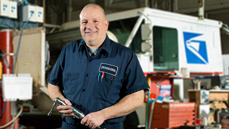 USPS Automotive technician checking a tire of a truck