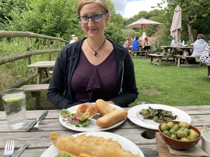 Jessica in a pub garden with a table full of food.