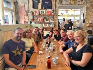 A brunch table with me and eight friends all smiling.