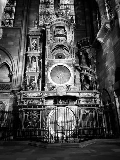 An astronomical clock in a cathedral with vertical layers of circular mechanisms piled up in a tower.