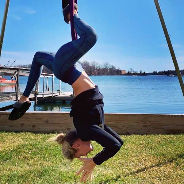 woman on outdoor aerial yoga rig doing pigeon pose