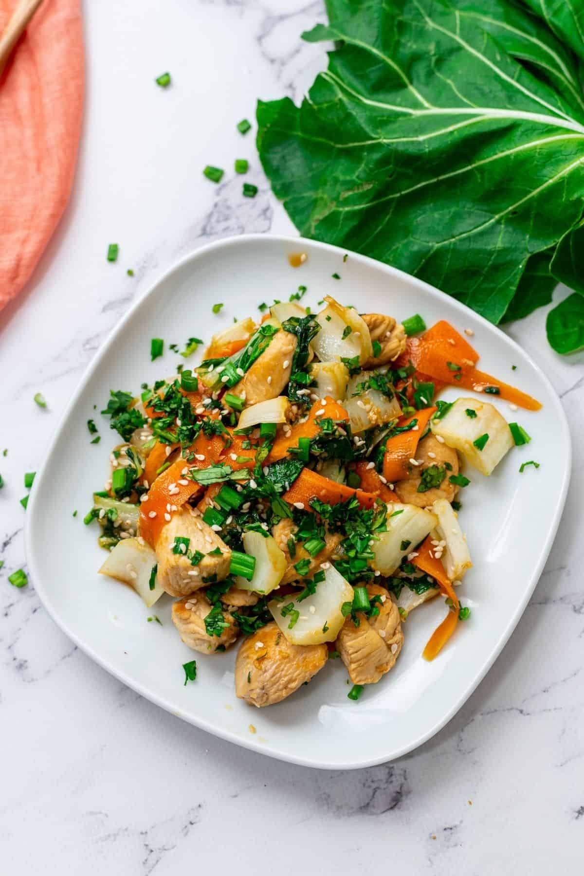 Plate of Chicken and Bok Choy stir fry next to fresh bok choy.