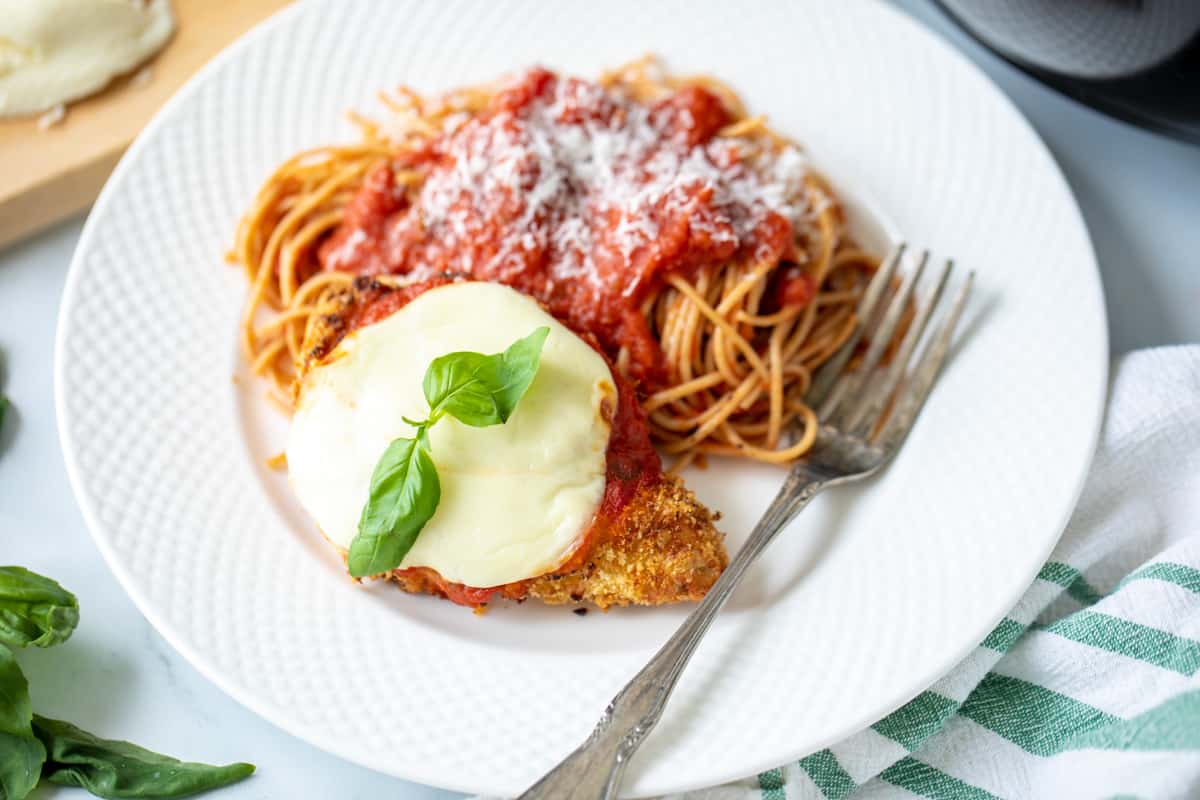 Air Fryer Chicken Parmesan on a plate with a side of spaghetti.