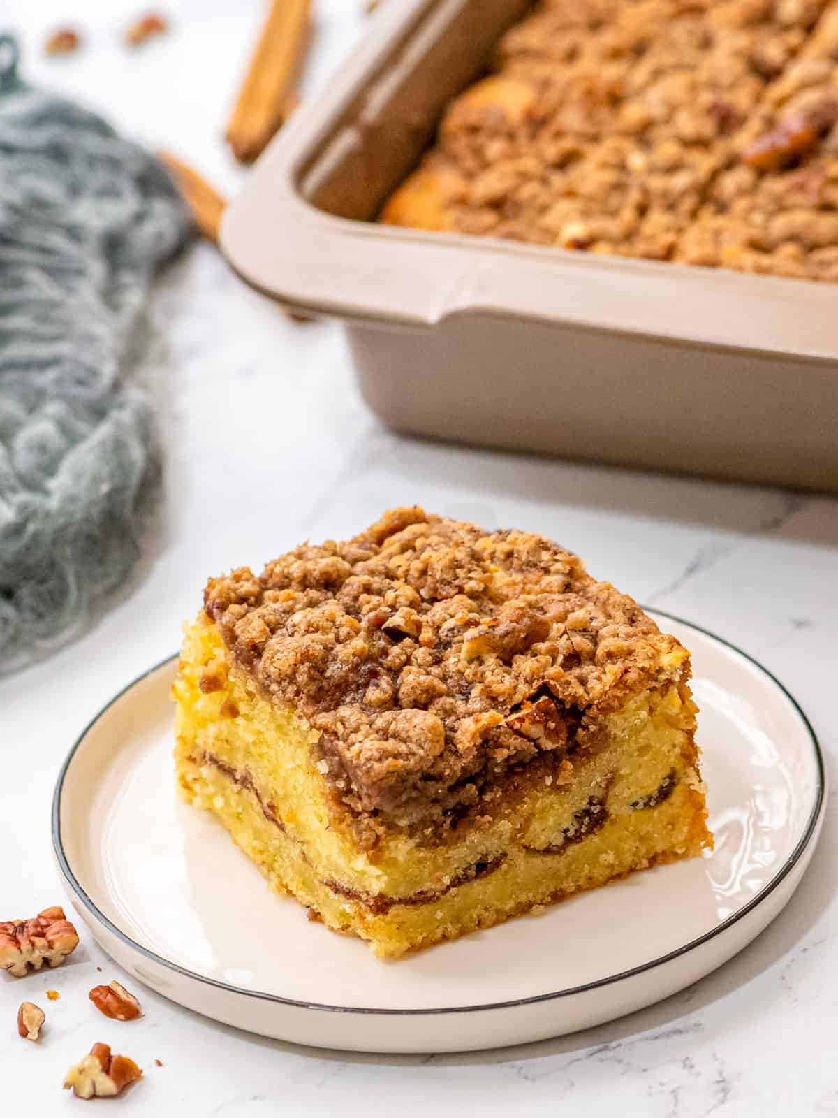 Piece of coffee cake on plate next to baked cake.