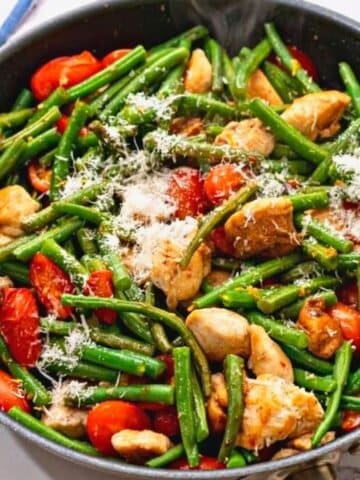 Skillet with chicken, tomatoes, green beans, and tomatoes.