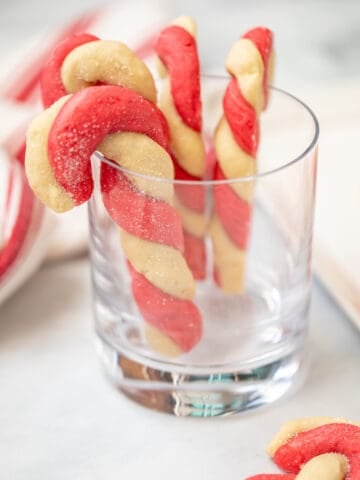 Candy Cane cookies hanging on a clear drinking glass.