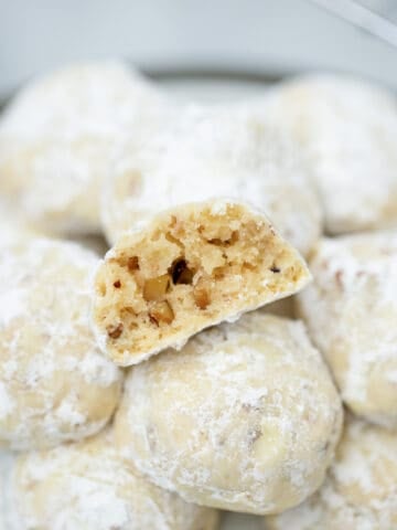 Snowball cookies on platter with one cut in half.