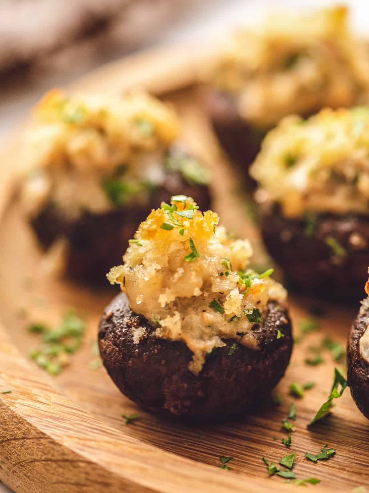 Close up of stuffed mushroom on wooden platter.