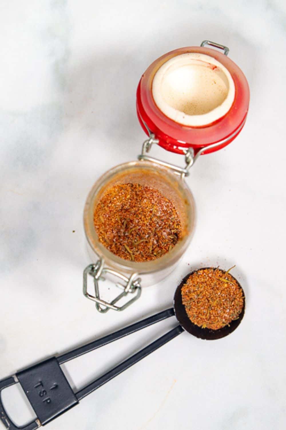 Jar of seasoning blend with measuring spoon.