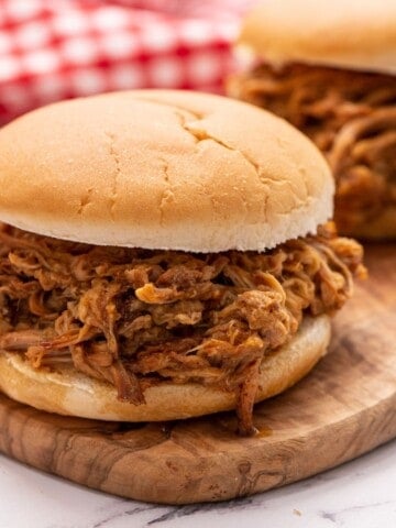 Pulled Pork on bun on cutting board.