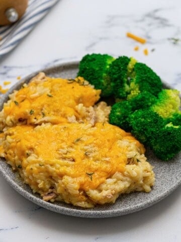 Chicken and Rice Casserole plated on gray plate next to steamed broccoli.