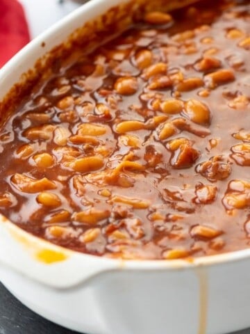 Saucy brown sugar baked beans in large white casserole dish.