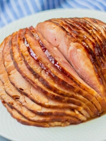 Instant Pot spiral sliced ham glazed in honey pineapple glaze on white platter next to electric pressure cooker.