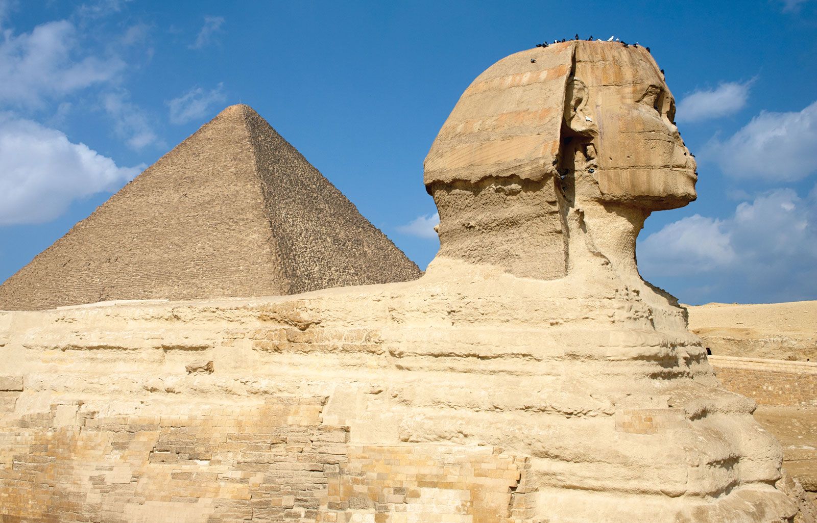 Al-Jizah. Giza Necropolis, Giza Plateau, Cairo, Egypt. Side view of Sphinx with the Great Pyramid of Khufu (Cheops) rising in the background. The sides of all three of the Giza pyramids are astronomically oriented to be north-south, east-west (see notes)