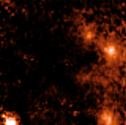 The image is a pixelated mapping of the hydrogen emission of the region around the star pair D9. Bright orange to white patches represent high hydrogen levels (indicating stars), black, represents very low hydrogen emission. Most of the centre of the image is dark with a few wisps of dark orange. The supermassive black hole Sagittarius A* is not discernable. D9 is showing as a bright orange patch near the top right of the image. Two other bright orange-reddish patches are at the right, another is at the bottom left.