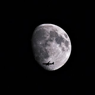 Plane flies in front of the moon