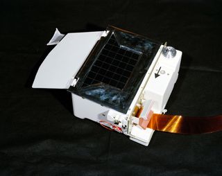 Lunar Atmospheric Composition Experiment looks like a large white box with a dark black rectangle in the center and what looks like a golden yellow ribbon trailing off it in the lower right corner.