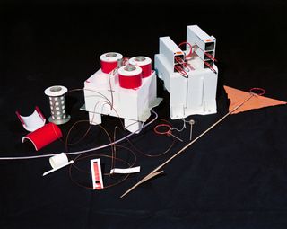 An assortment of equipment including red wires and what looks like a flag with two orange pieces of fabric on the end.