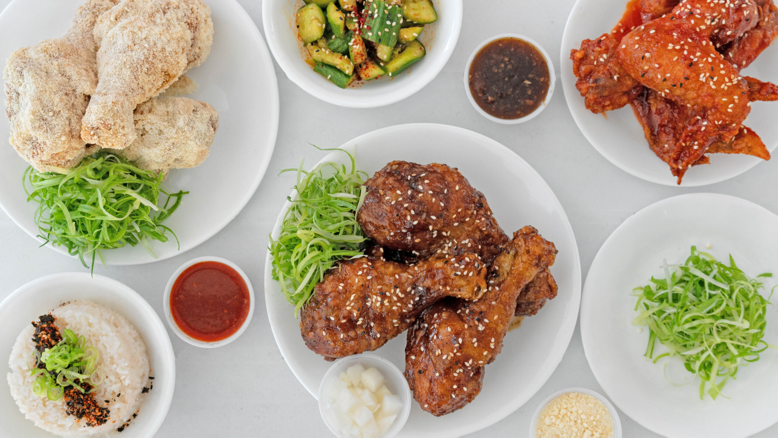 Three different varieties of fried chicken from Portland food cart Frybaby, plated alongside sides like garlic rice.