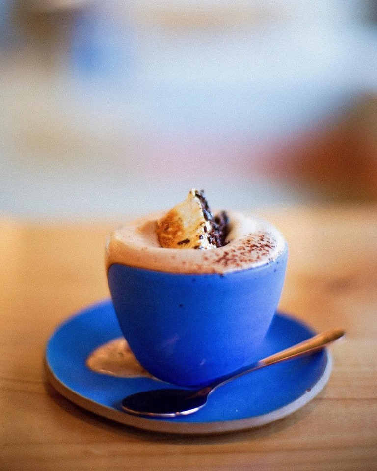 A cup of hot chocolate, garnished with a frankincense marshmallow, sits on the bar of Cloudforest Chocolate’s cafe