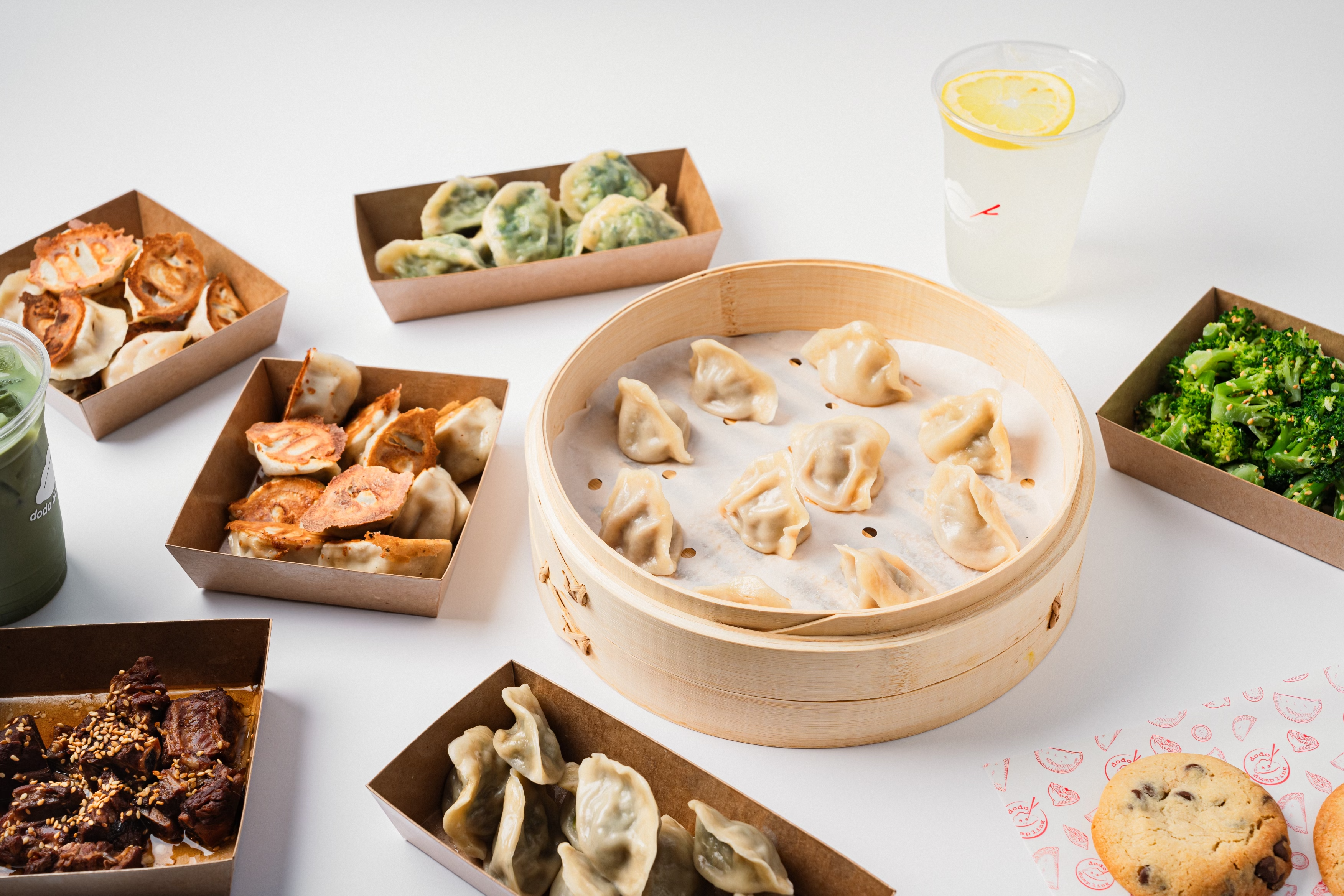 Curated spread of dumpling and vegetable dishes atop a white table background.