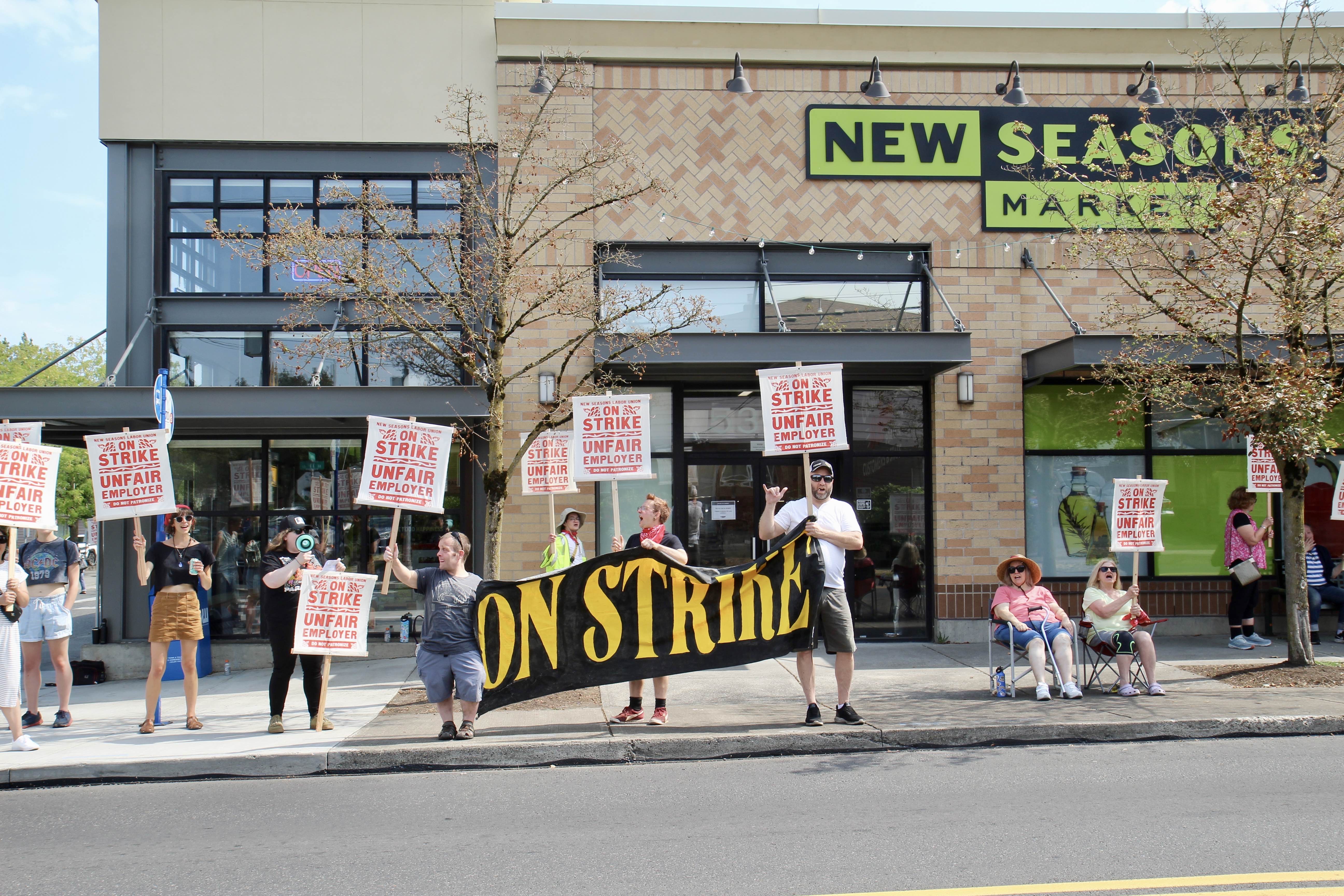 Workers hold up signs outside of New Seasons Market in Portland, Oregon on strike