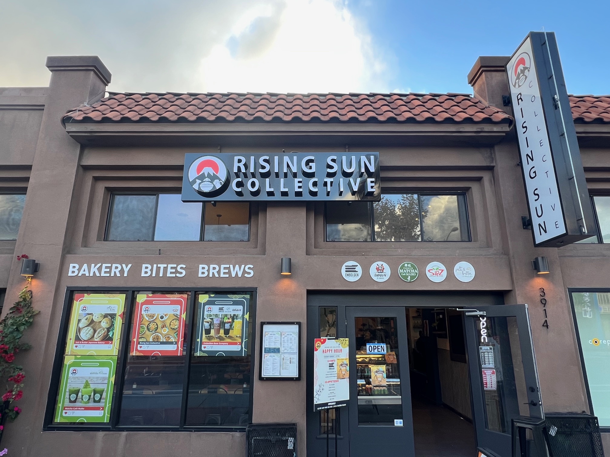 The exterior of rising sun collective says bakery bites brews.