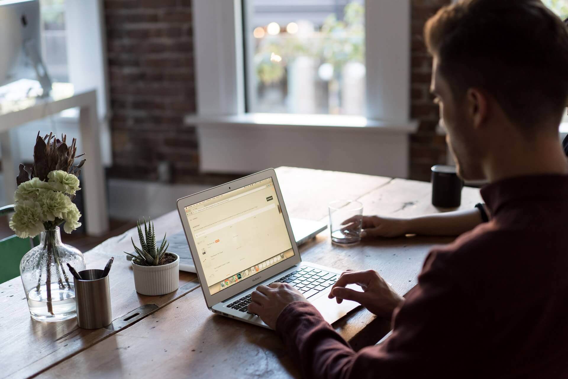 Two people sitting next to each other and collaborating over a shared laptop