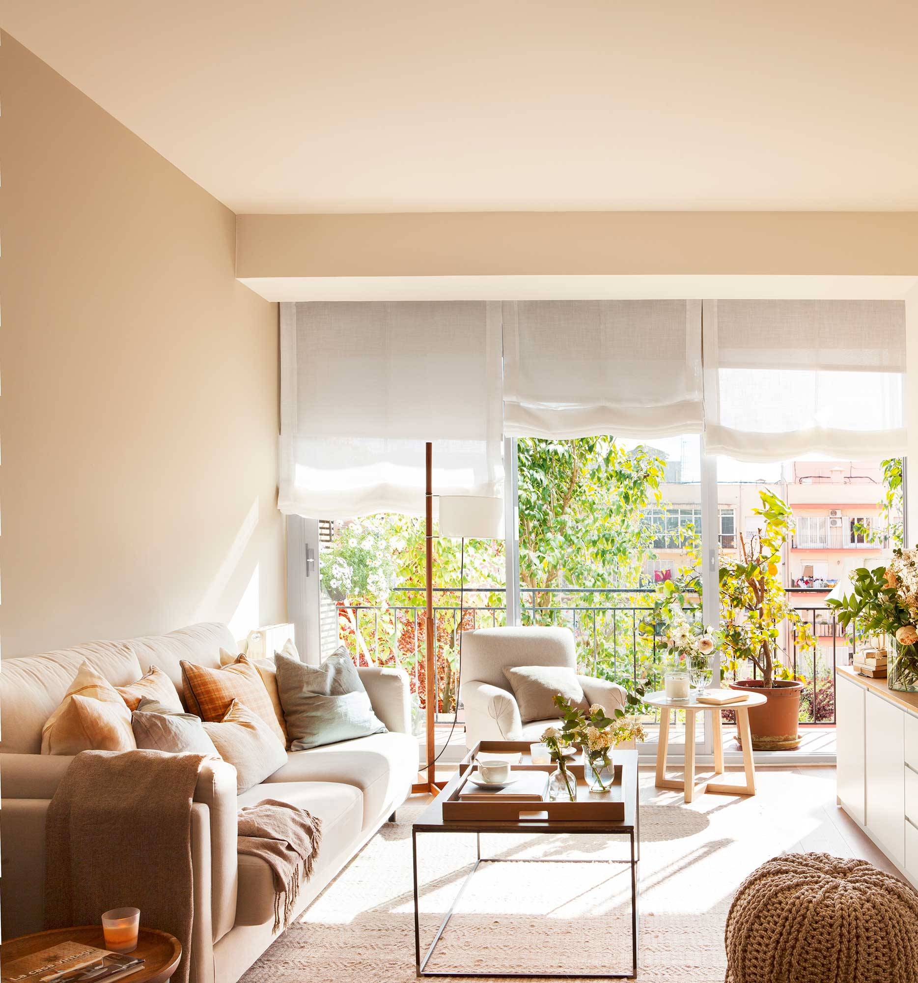 Salón con paredes y sofá beige con mesa de centro de madera. 