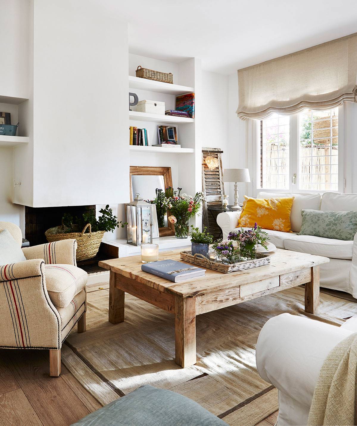 Salón con chimenea, sofá blanco y mesa de centro de madera. 