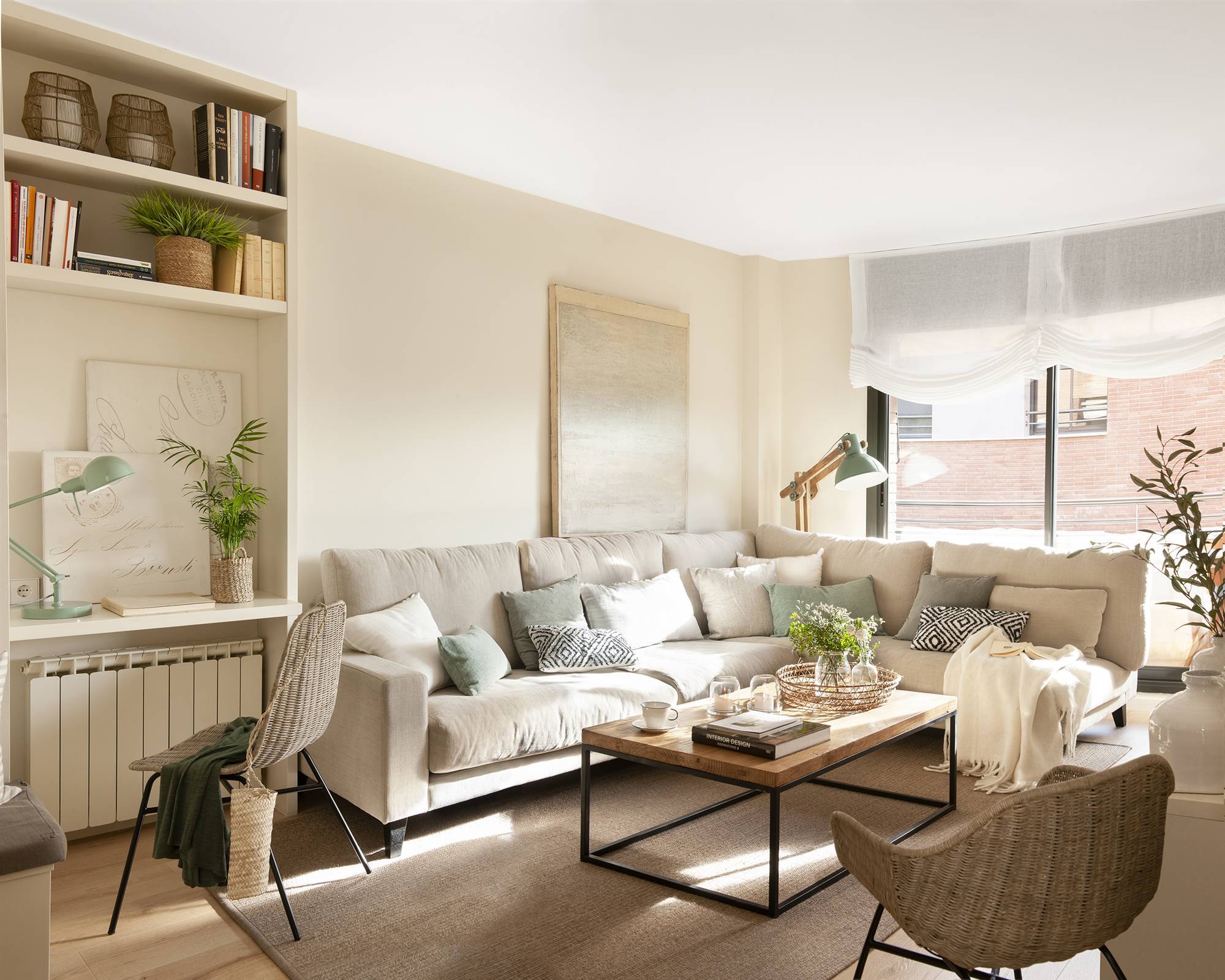 Salón pequeño con sofá rinconero en gris claro y mesa de centro de madera. 