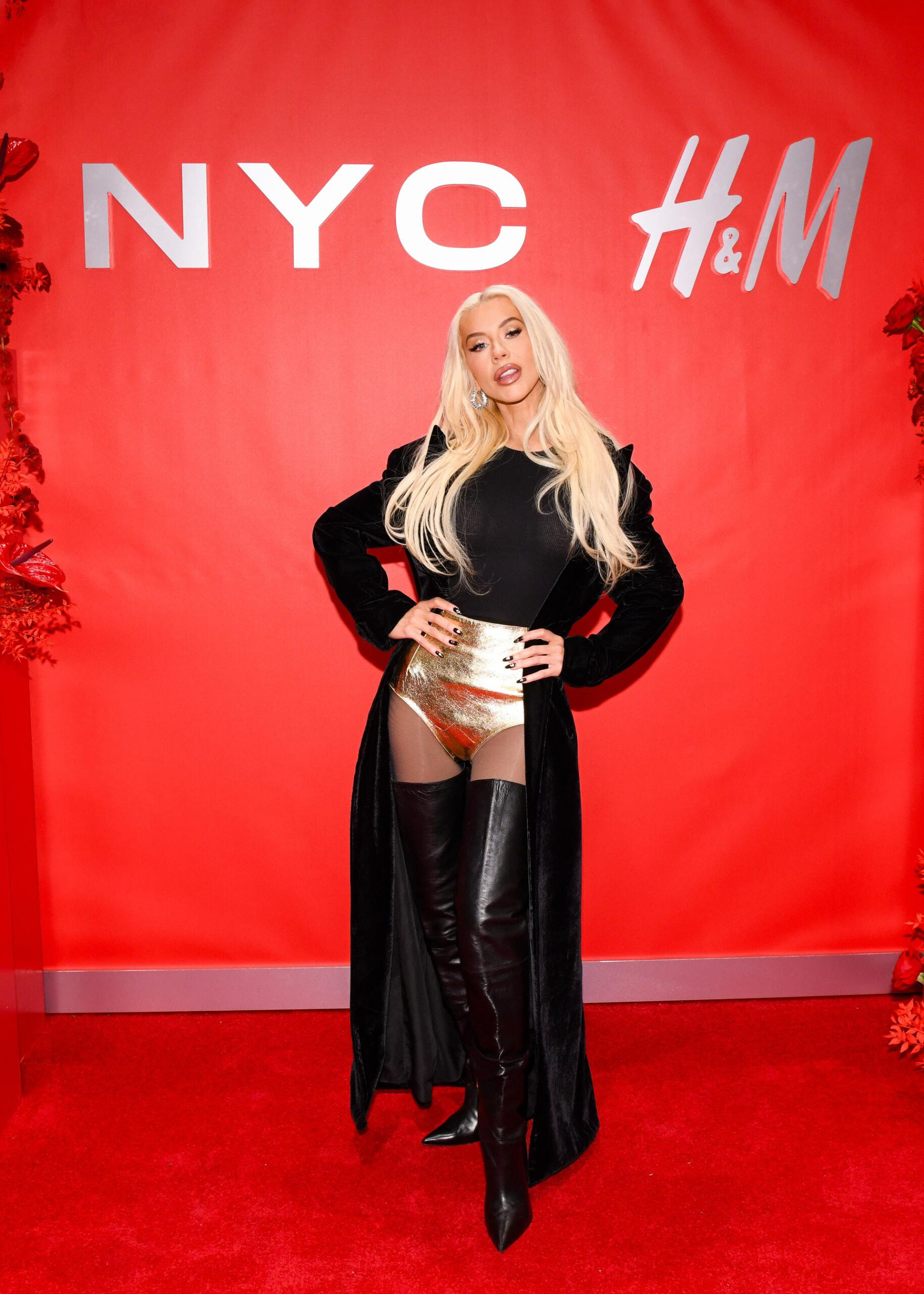 Christina Aguilera arrived at the H&M ribbon cutting ceremony on Wednesday in a dazzling pop star ensemble. To celebrate the Times Square flagship store reopening, the multi-hyphenate icon and Grammy winner rocked an edgy and metallic look with high waisted gold shorts, apart of H&M’s Studio Holiday capsule, a black top, black floor length velvet jacket, and shiny black knee-high boots. Aguilera completed the festive look with black nails, silver earrings, and her signature Barbie blonde hair.Courtesy of H&M