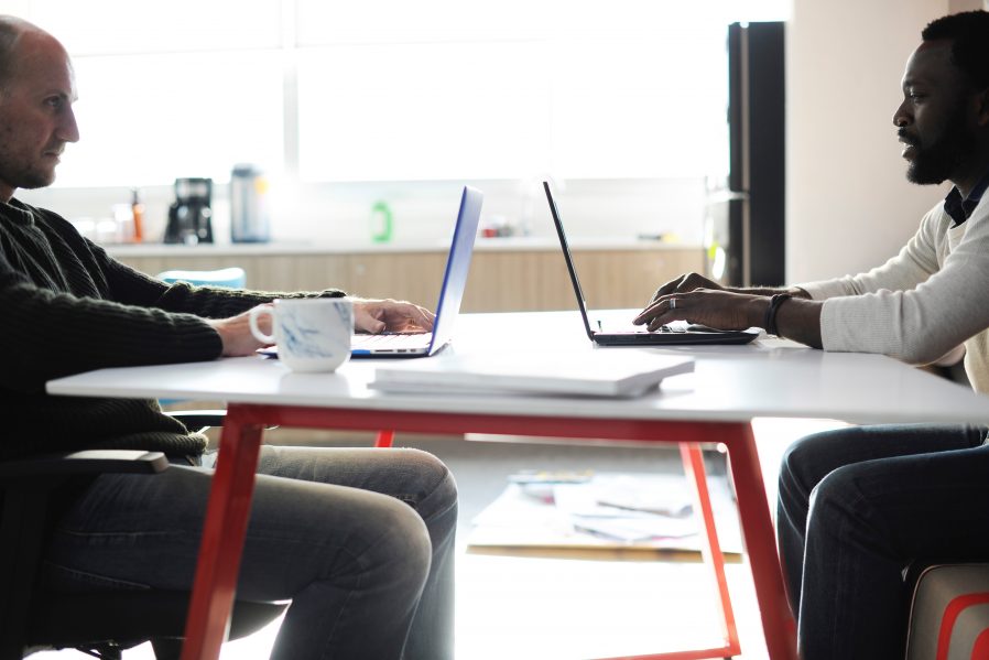 Two men using laptops opposite one another.