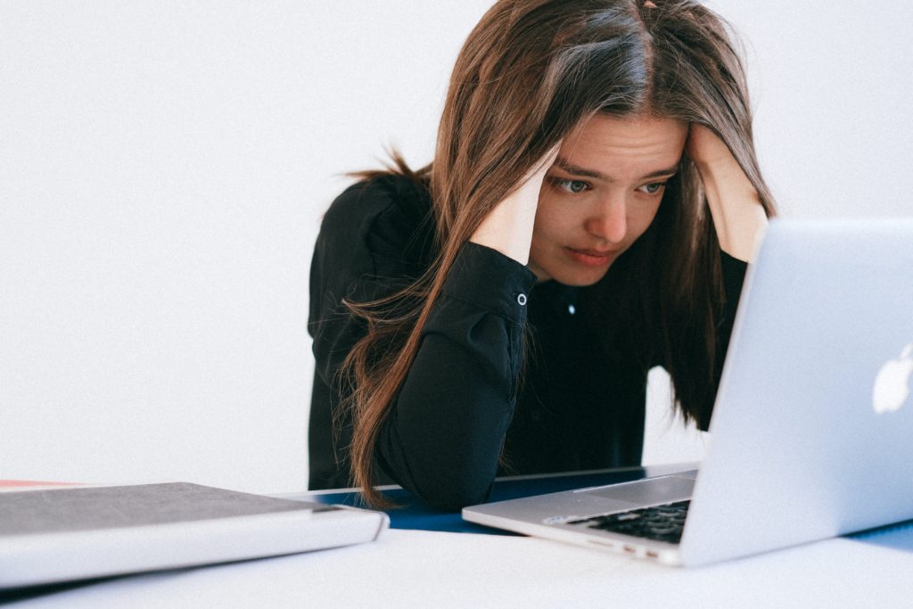 Stressed programmer hunched over a MacBook. Photo by Anna Shvets from Pexels.