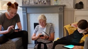 Two adults and a child using mobile phones and tablets.