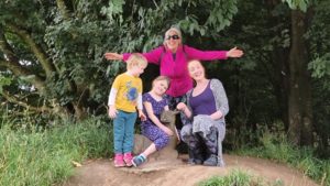 Two adults and two children pose with a wooden sculpture of a doe lying down.