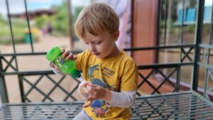 A boy pours a juice drink onto some candy floss.