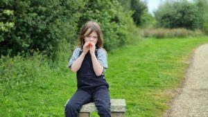 A girl plays a kazoo.