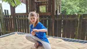 A girl digs in a tabletop sandpit.