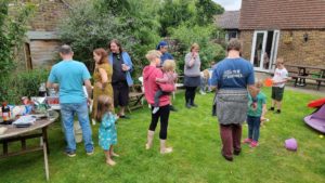 People stand around in a garden at a barbecue.