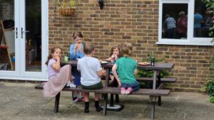 Children at a picnic table in a garden.