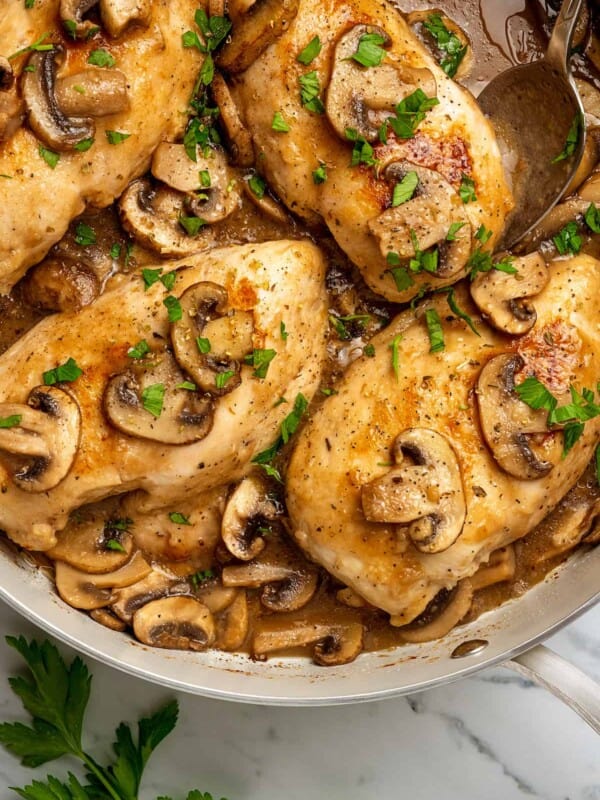 Top view of chicken marsala in a large skillet, topped with mushrooms and marsala wine sauce.