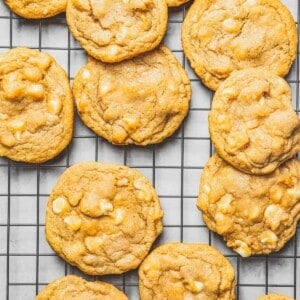 Overhead view of lots of white chocolate chip cookies on a wire cooling rack.