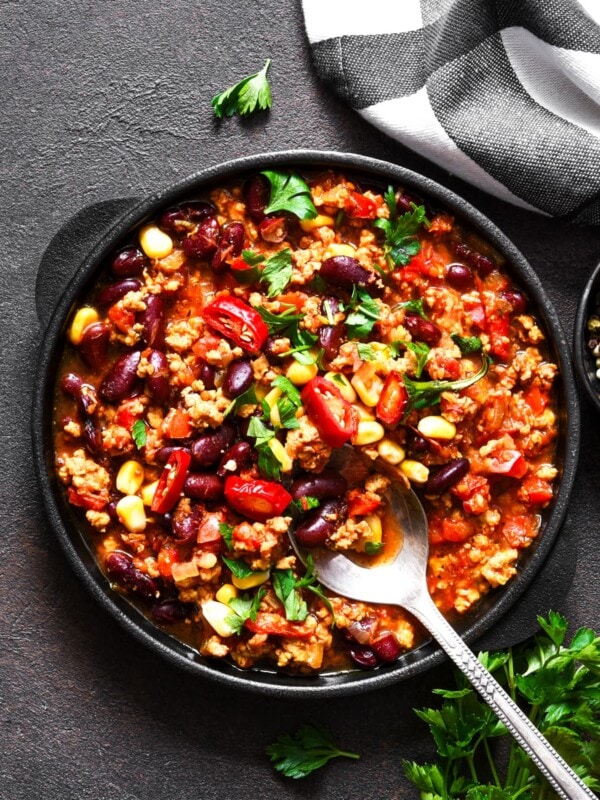 Overhead image of a burrito bowl in a dinner plate topped with chopped peppers and fresh cilantro.