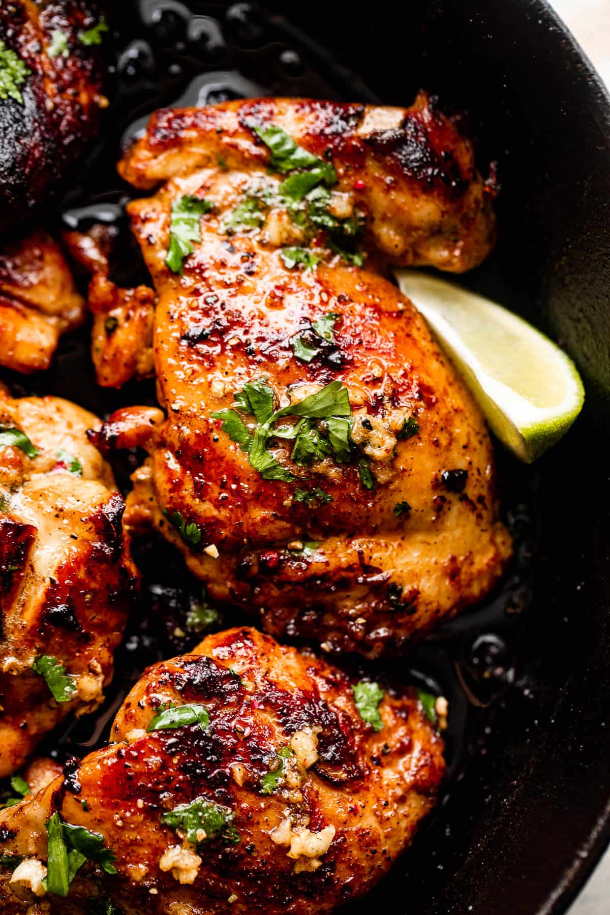 Close-up picture of cilantro chicken thighs with lime wedge next to the thighs.