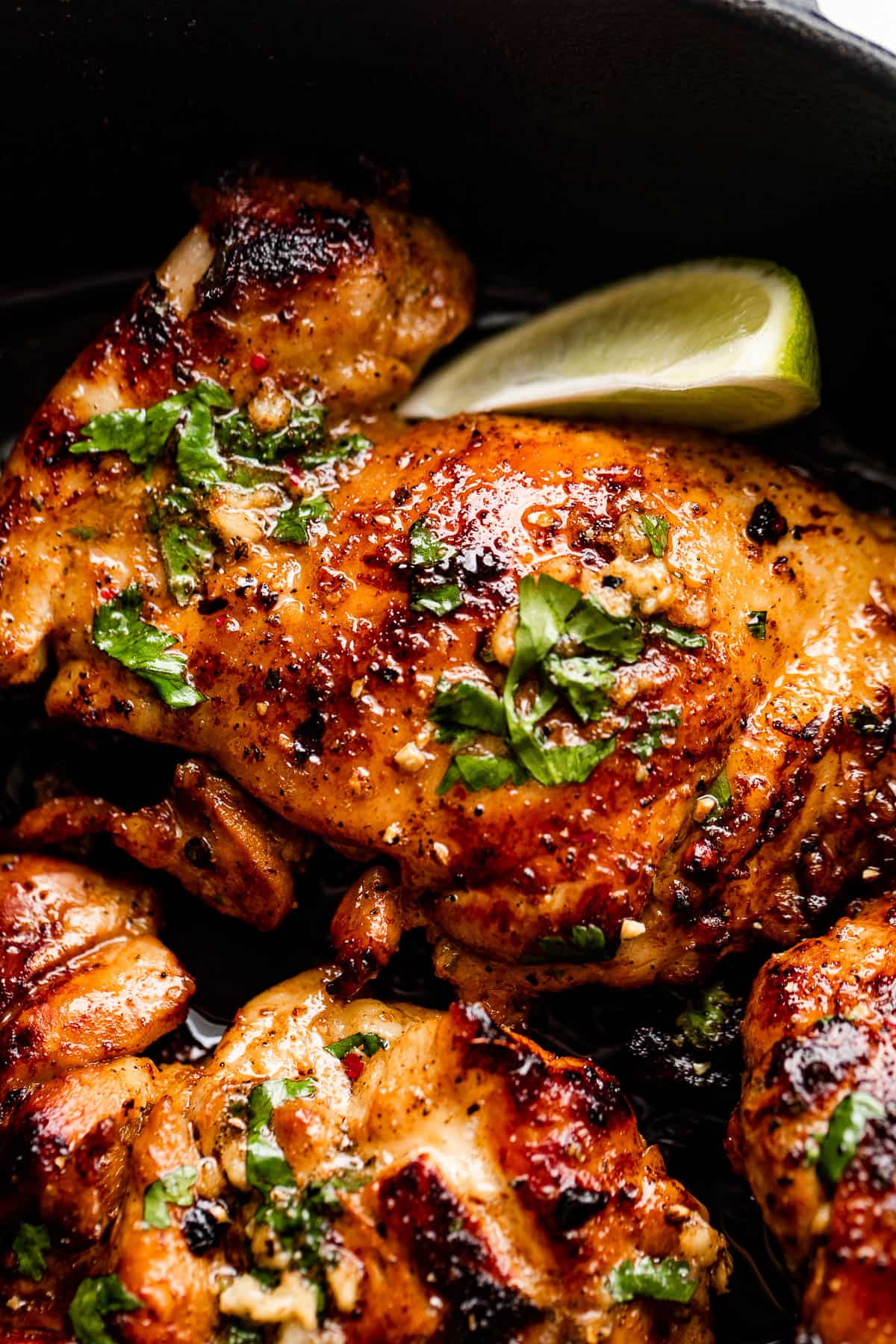 Up close photo of cilantro lime chicken thighs with a lime wedge set next to the thighs.