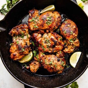 overhead picture of chicken thighs cooking in a cast iron skillet