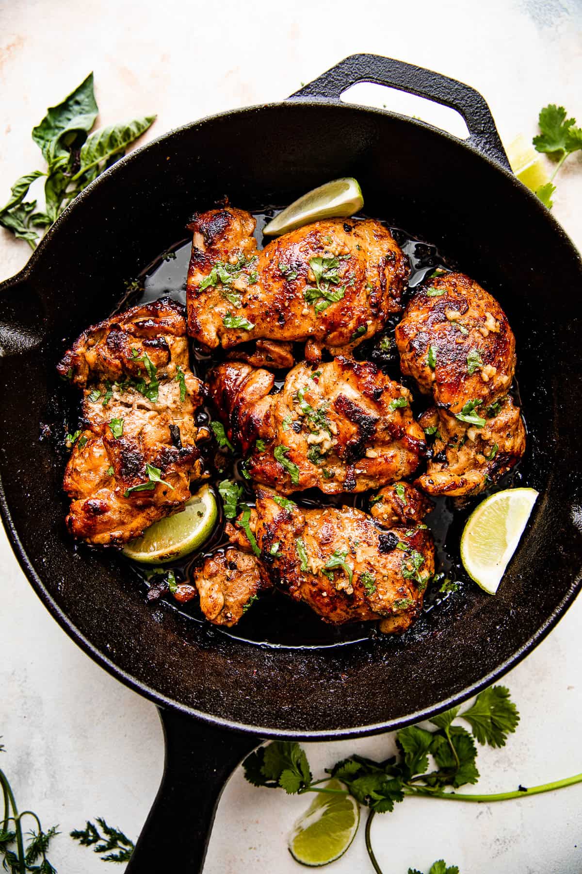 Overhead picture of chicken thighs cooking in a cast iron skillet.