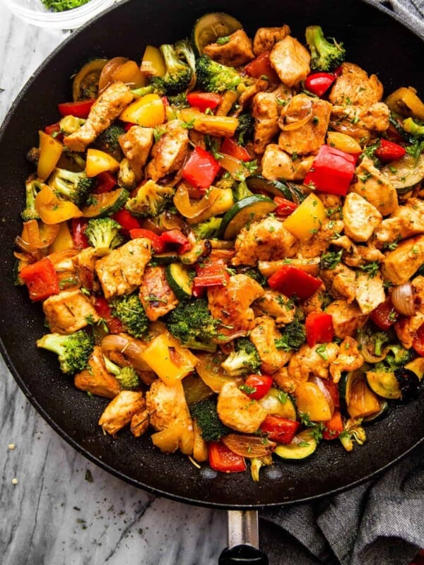 overhead shot of cut up chicken breast cooked in a skillet with zucchini, broccoli, and bell peppers