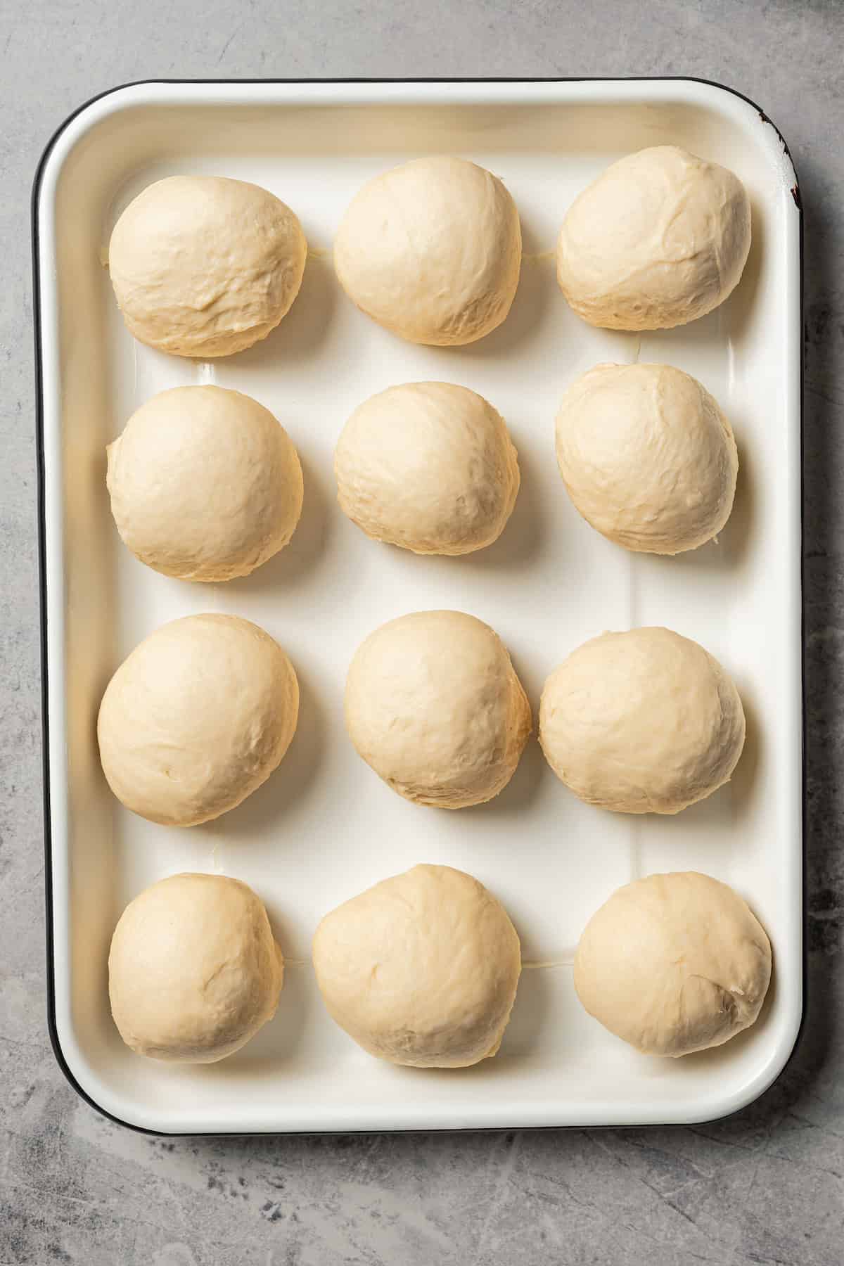 Dinner roll dough portioned into balls on a baking sheet.